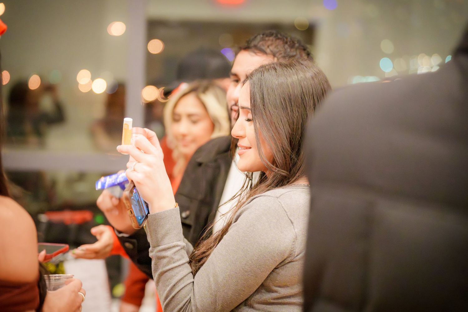 Blurred party scene with colorful bokeh lights and people socializing in the background.