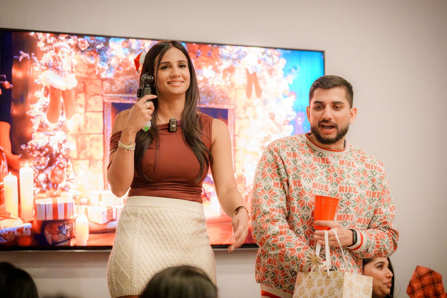 People gather in front of a large TV display at a social event.