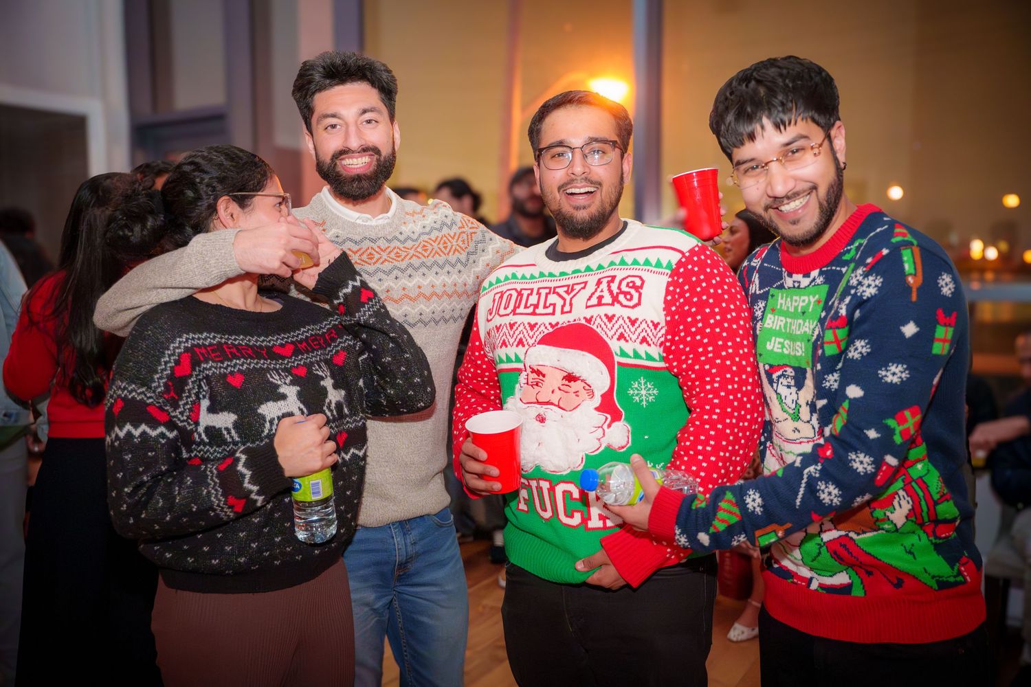 People wearing festive holiday sweaters at a Christmas party gathering.