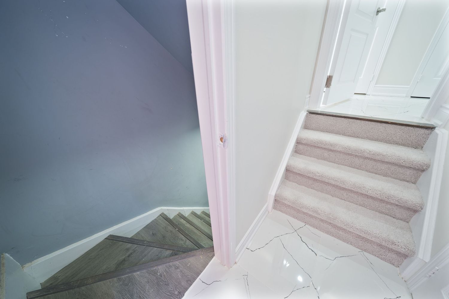 White painted staircase with carpeted steps turning at a corner in a residential home interior.
