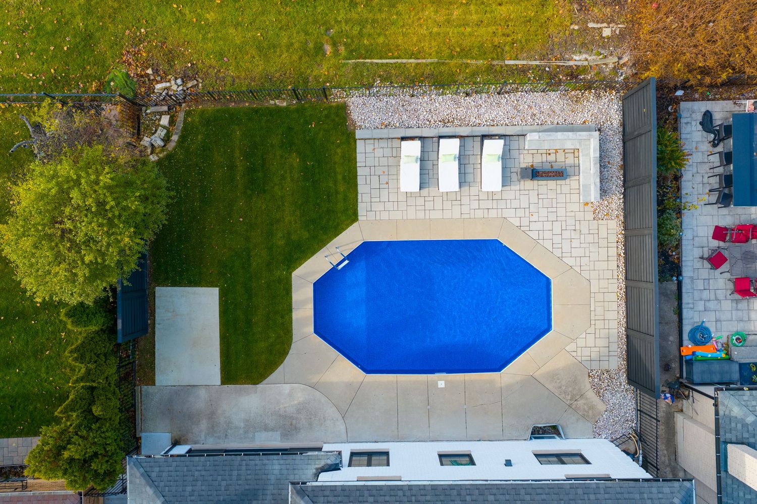Aerial view of a residential neighborhood with swimming pools and tennis courts surrounded by green trees.