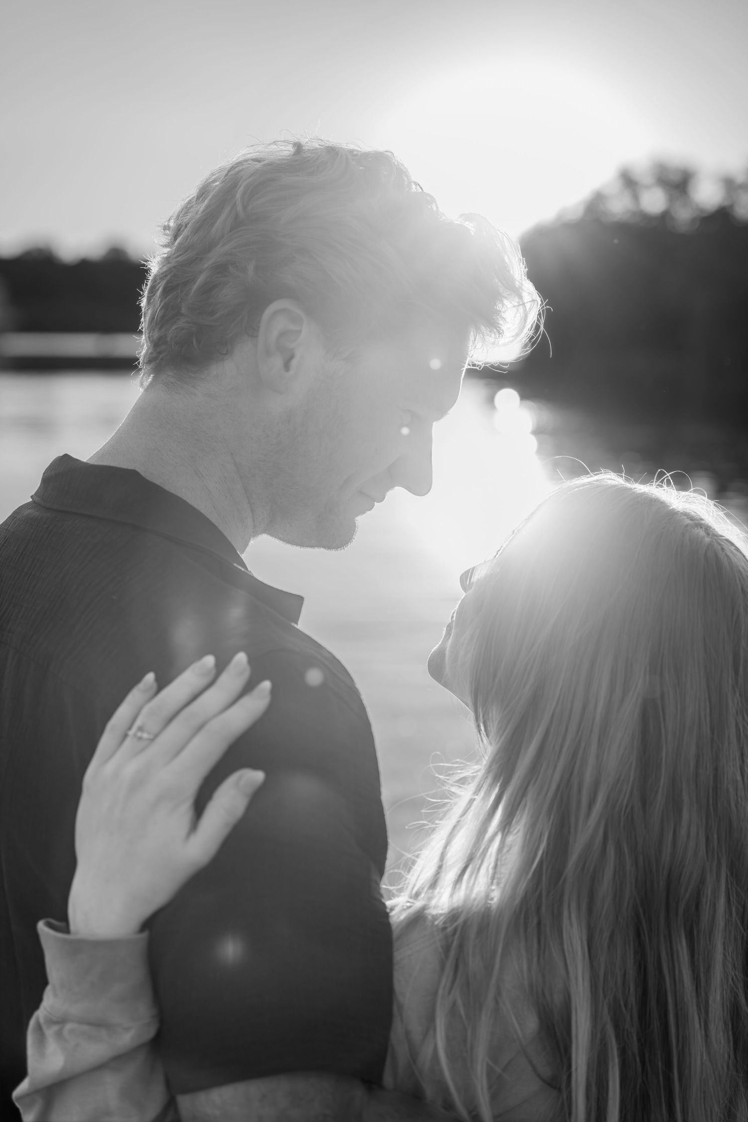 Black and white romantic couple portrait face to face in bright sunlight near a lake.
