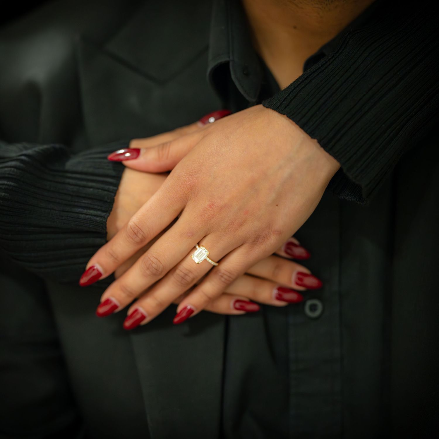 Close up of engagement ring on hand with red manicured nails.