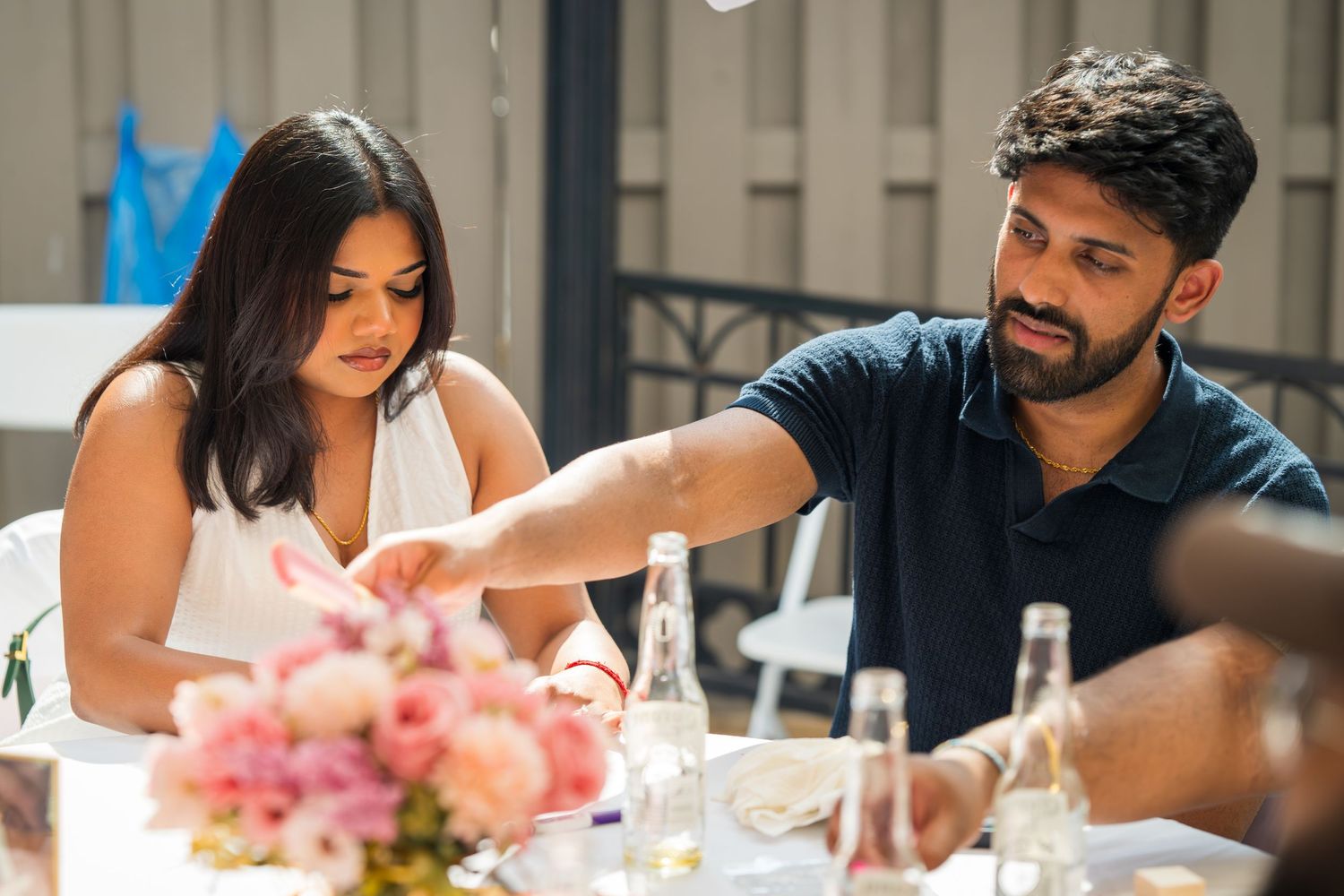 Guests seated at elegant tables with pink floral centerpieces during a celebration.