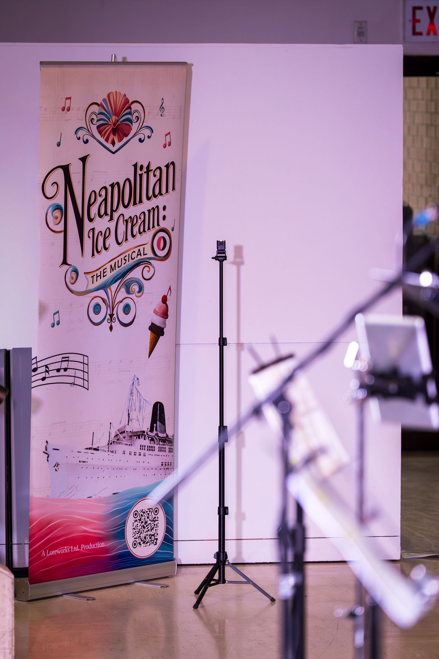 Neapolitan Ice Cream The Musical promotional banner displayed on a stand next to microphone stands.
