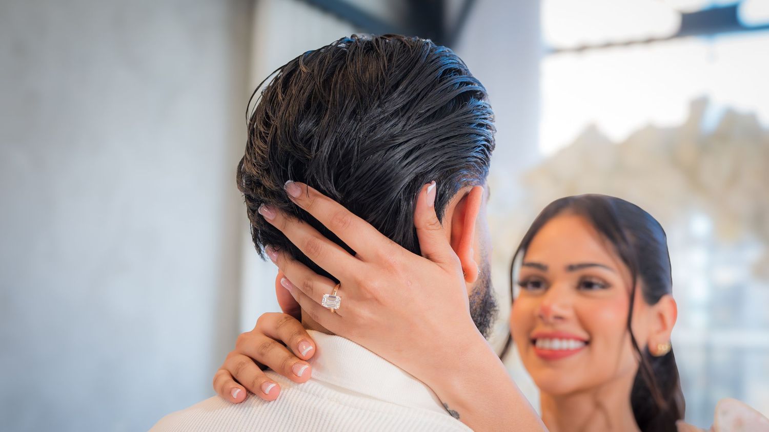 Newly engaged woman smiling and touching man's face showing off her diamond engagement ring.