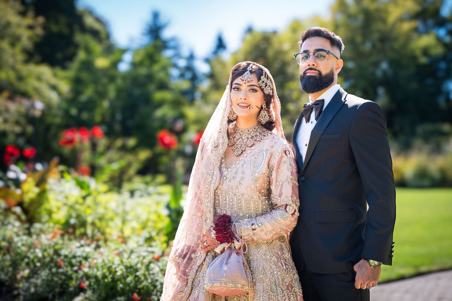 A couple shares a romantic moment in an outdoor garden setting with vibrant greenery.