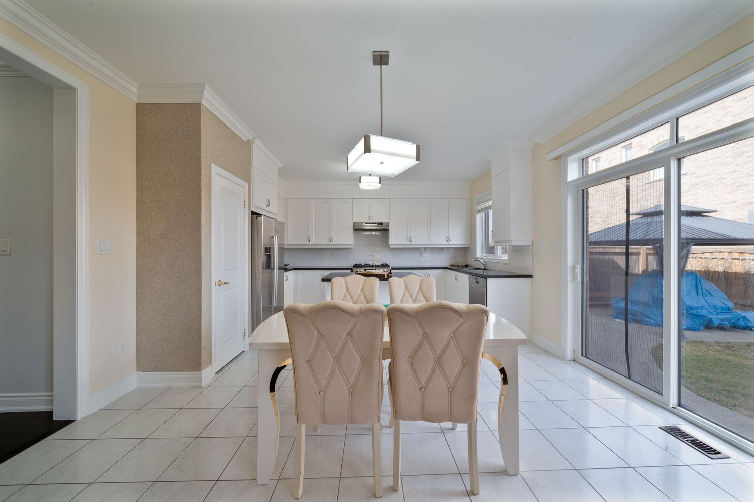 Modern open concept living room with white walls, tiled floors, and large windows letting in natural light.