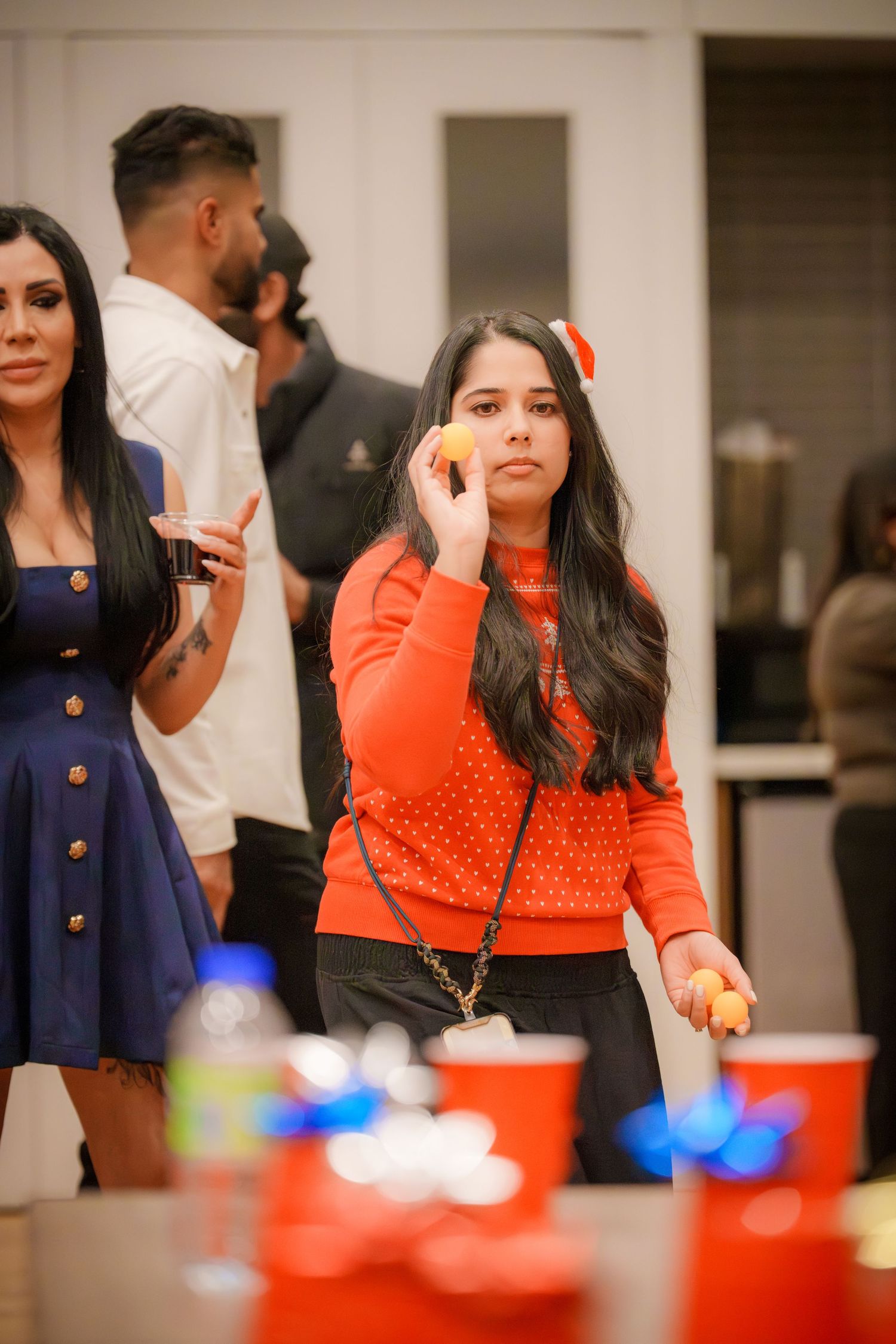 Person in bright orange sweater participates in party activities at a decorated table.