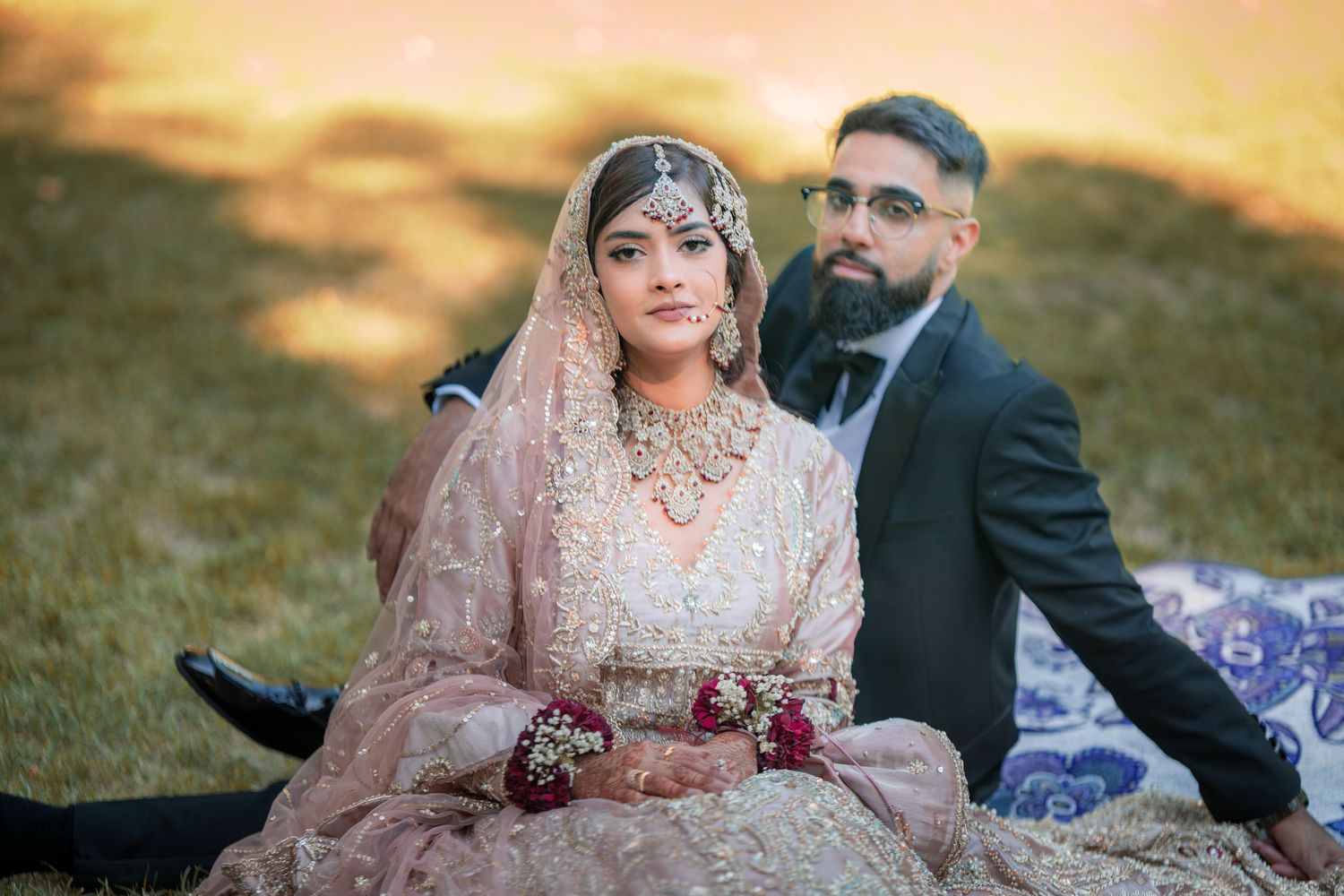 A couple sits together during their wedding photoshoot at sunset.