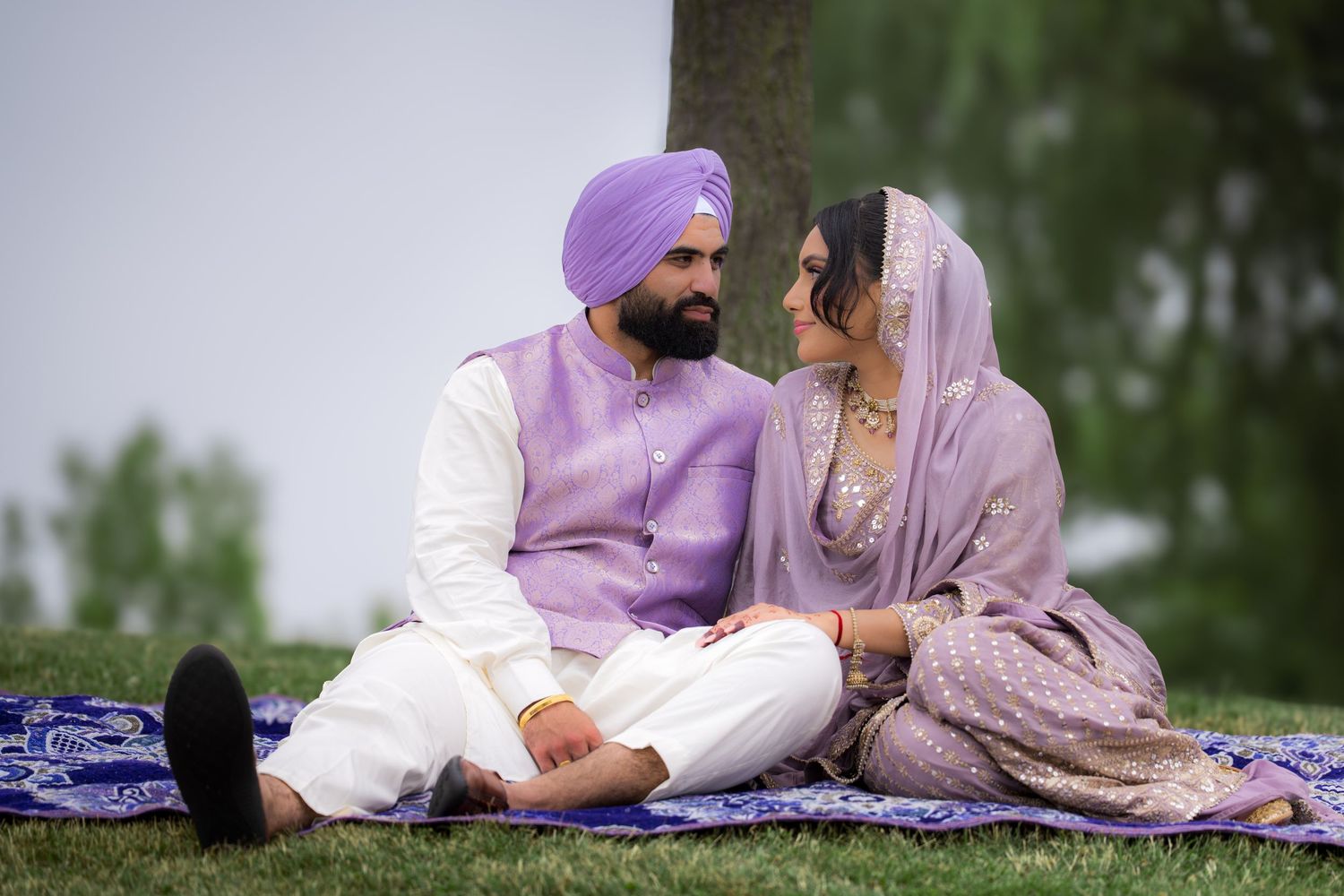 A couple in traditional Punjabi dress sharing a tender moment during their outdoor photoshoot.