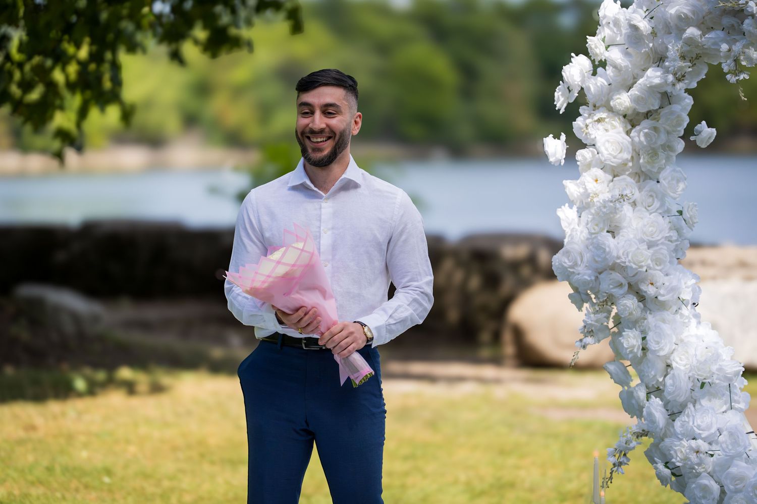 An outdoor wedding venue features elegant white balloon decor against a scenic waterfront backdrop.