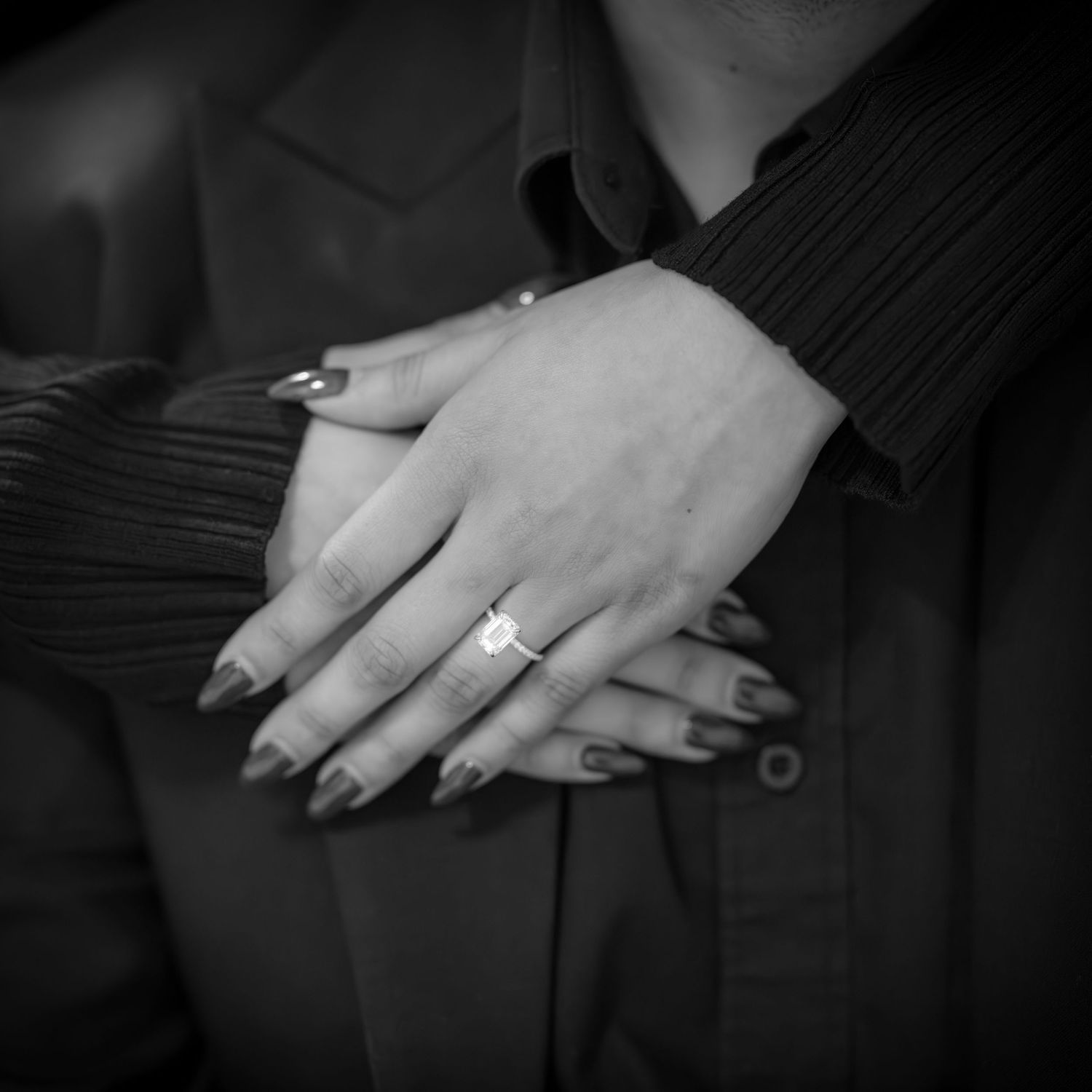 Close-up of hands showing engagement ring in black and white.