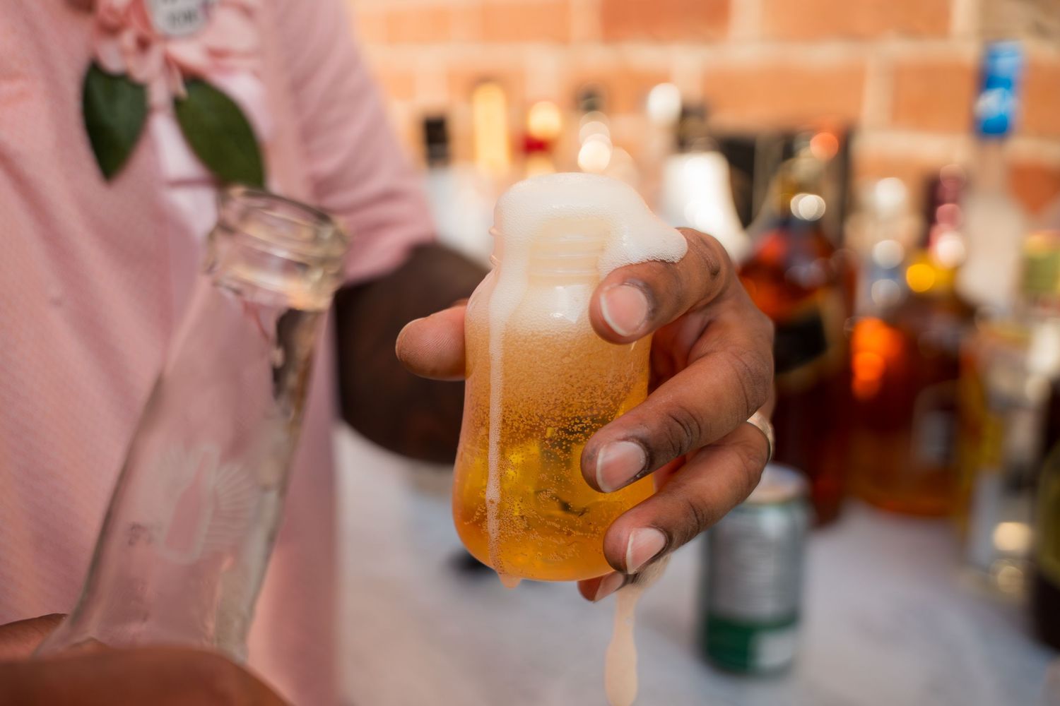 Multiple hands holding drinks at a celebration event with peach-colored lighting.