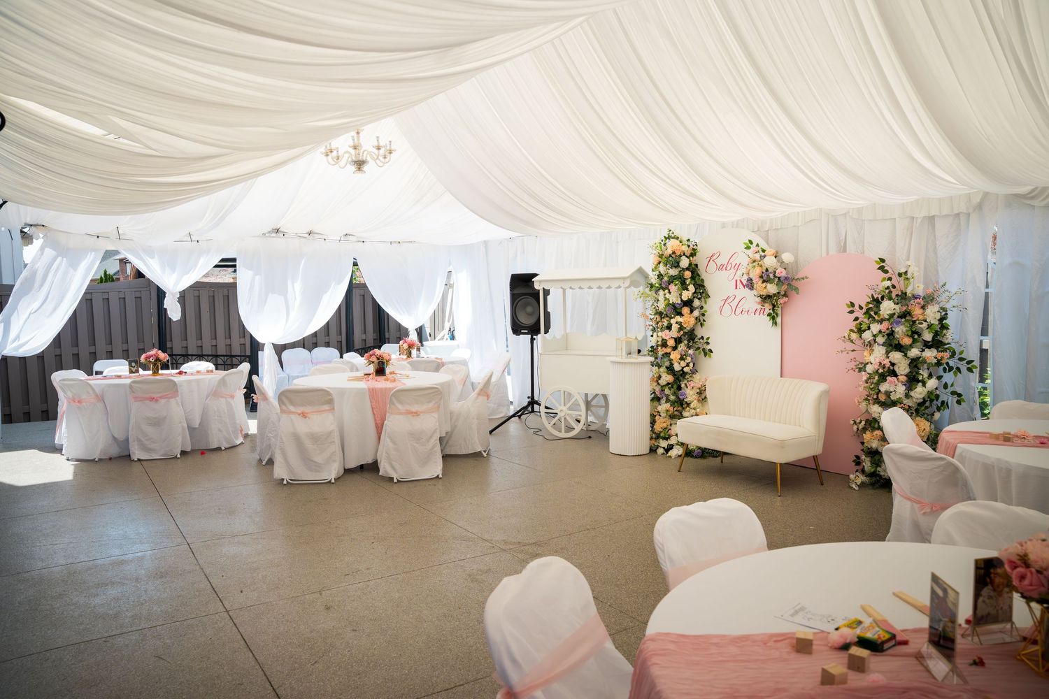 Elegant white wedding reception venue with draped fabric ceiling and floral arrangements.