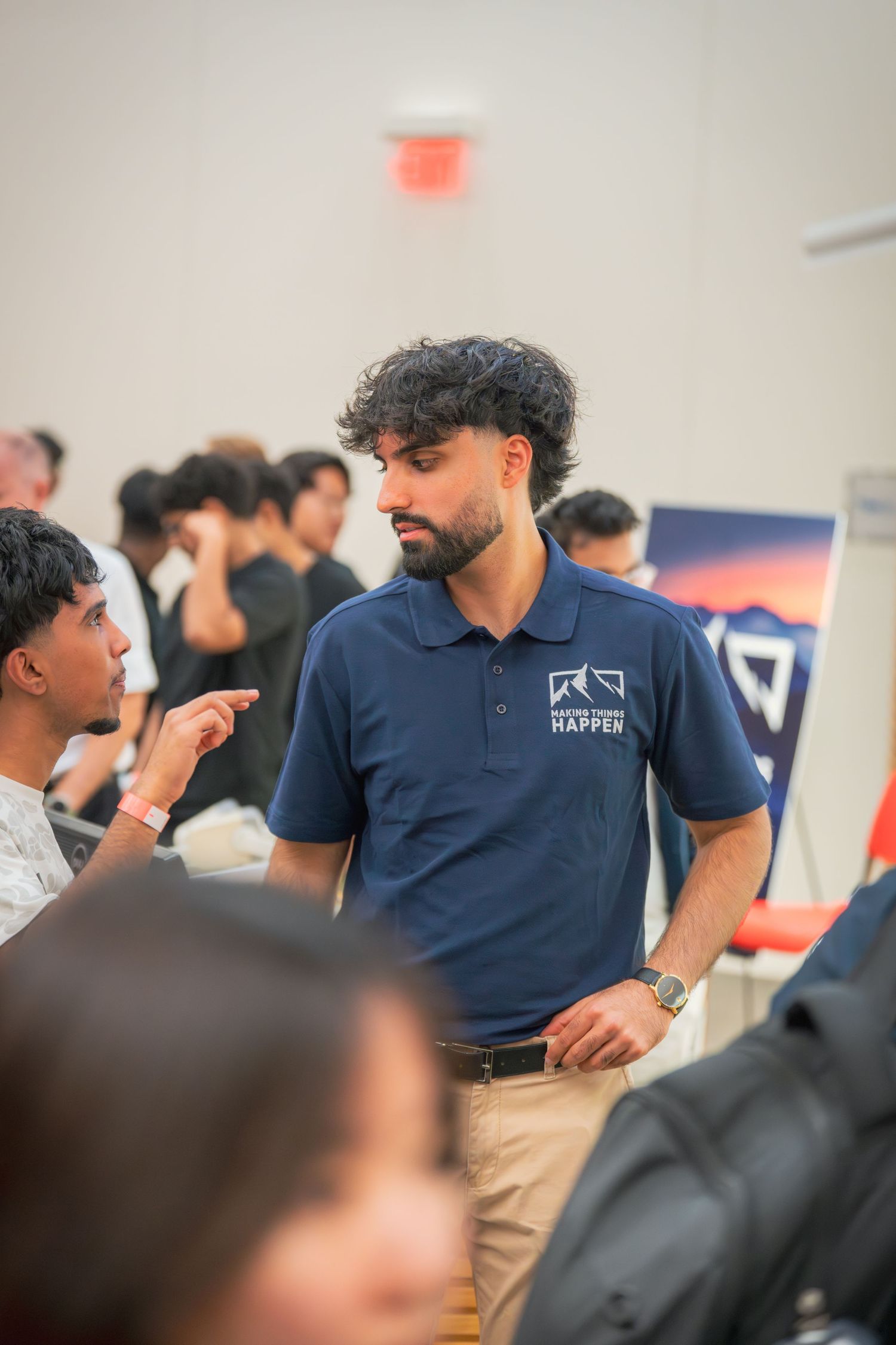 Staff members in navy polo shirts interacting with attendees at an educational event.