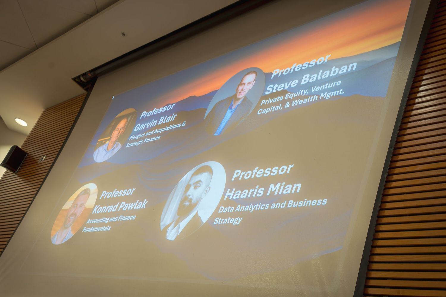 Multiple projection screens showing presentation content in a professional conference setting.