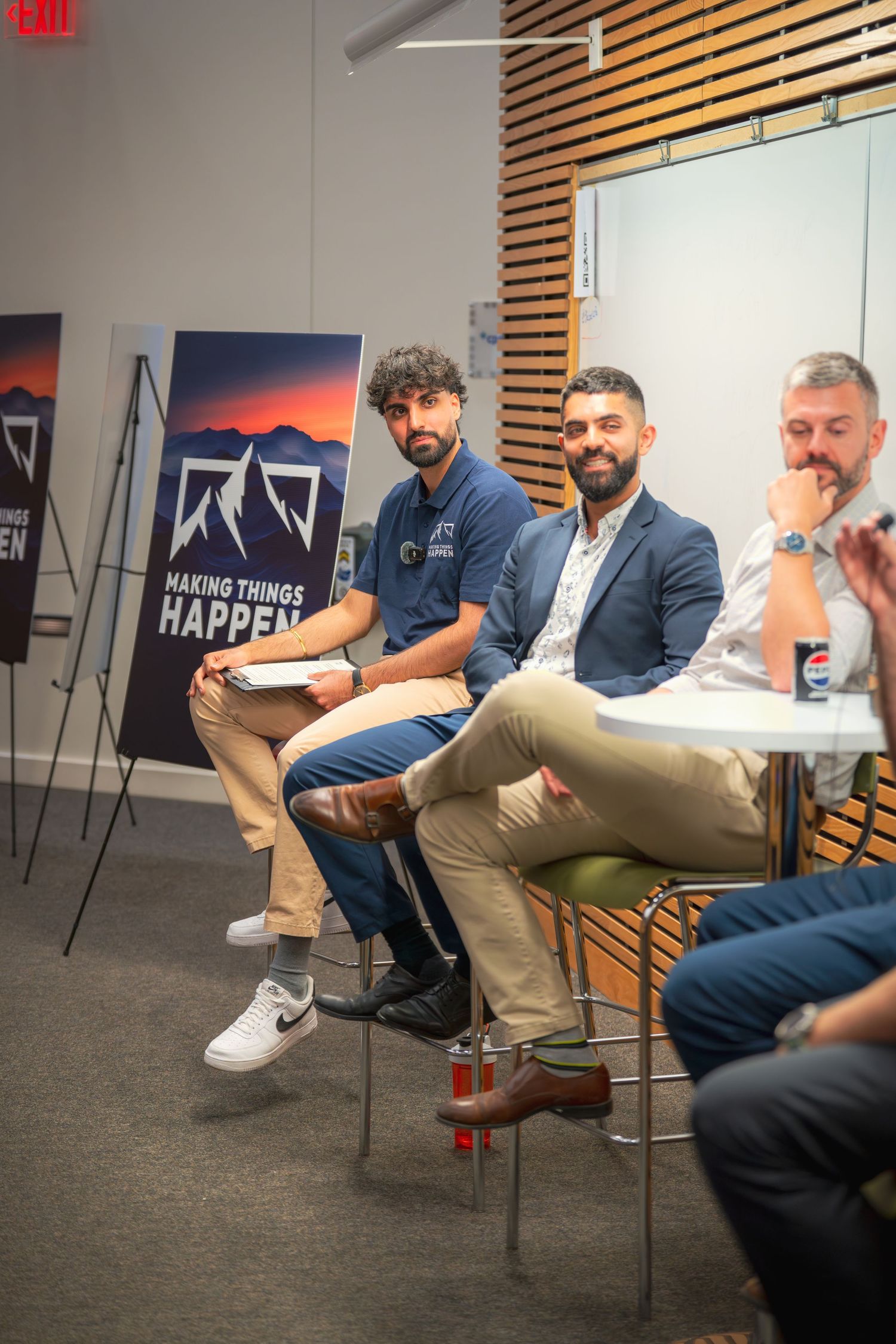 A group sits casually in chairs during a presentation with a 'Making Things Happen' banner visible.
