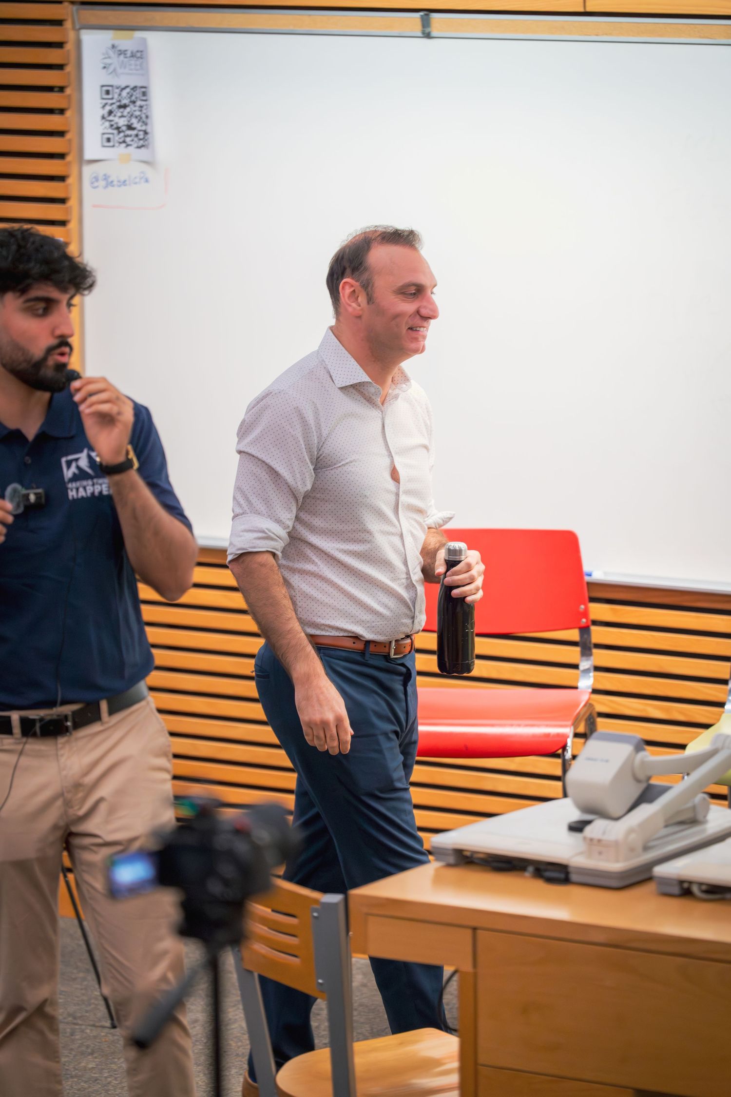 Two presenters standing at the front of a classroom during a presentation.