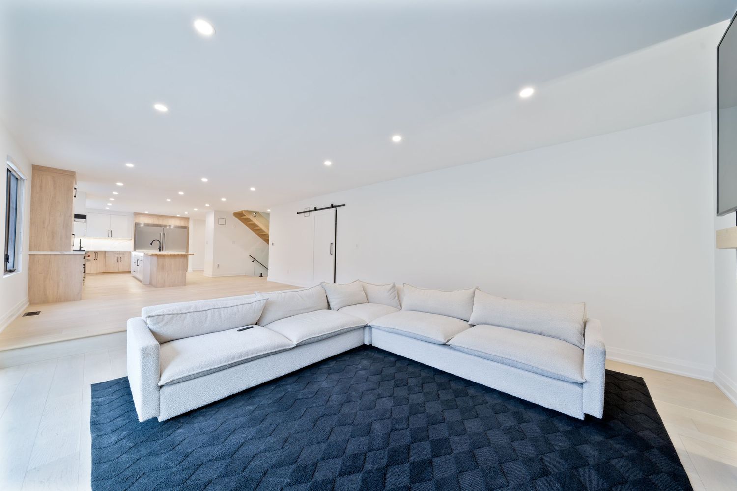 Modern white bedroom interior with recessed lighting, hardwood floors and built-in storage cabinets along the wall.