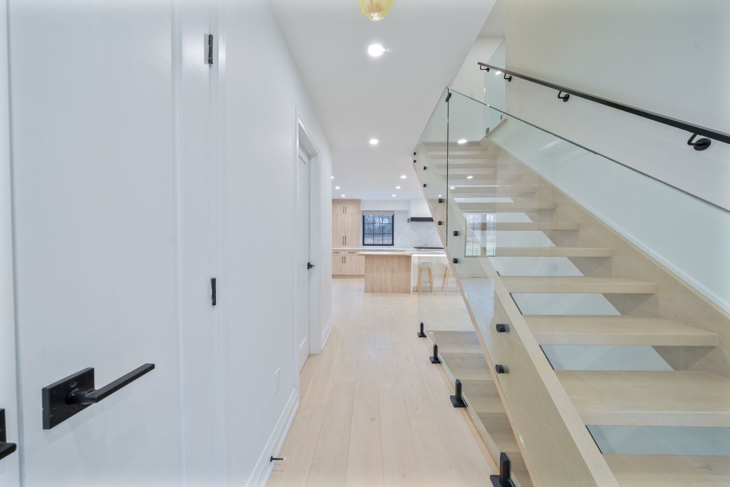 Modern yoga studio with light wood floors, white walls, and glass partitions creating a bright, minimalist exercise space.