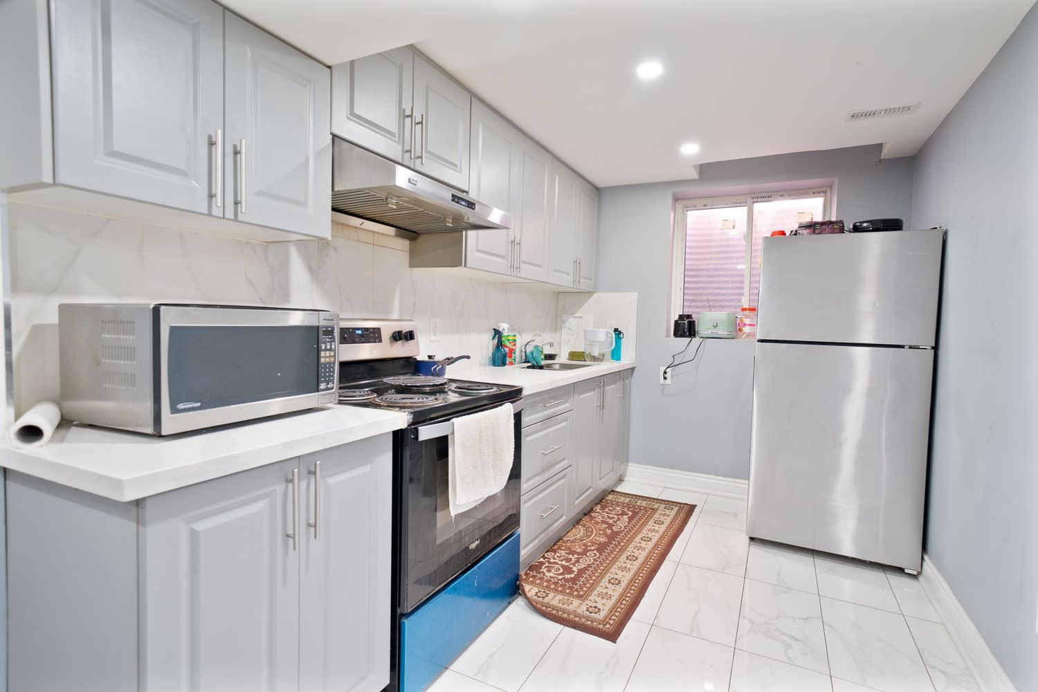 Modern white kitchen interior with stainless steel appliances and recessed lighting showcases sleek cabinetry and clean lines.