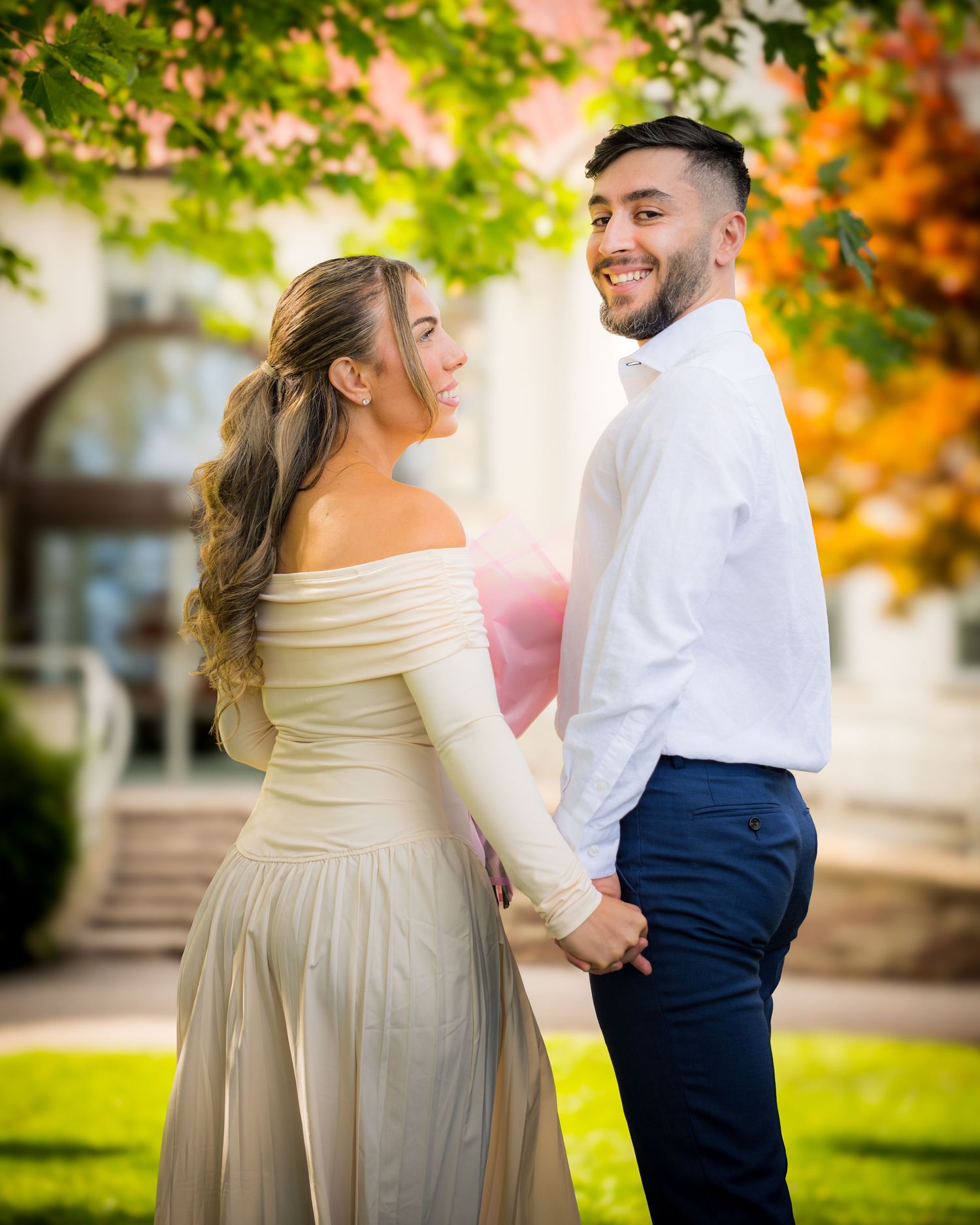 A tender moment between a couple in formal wear under golden sunlit trees.