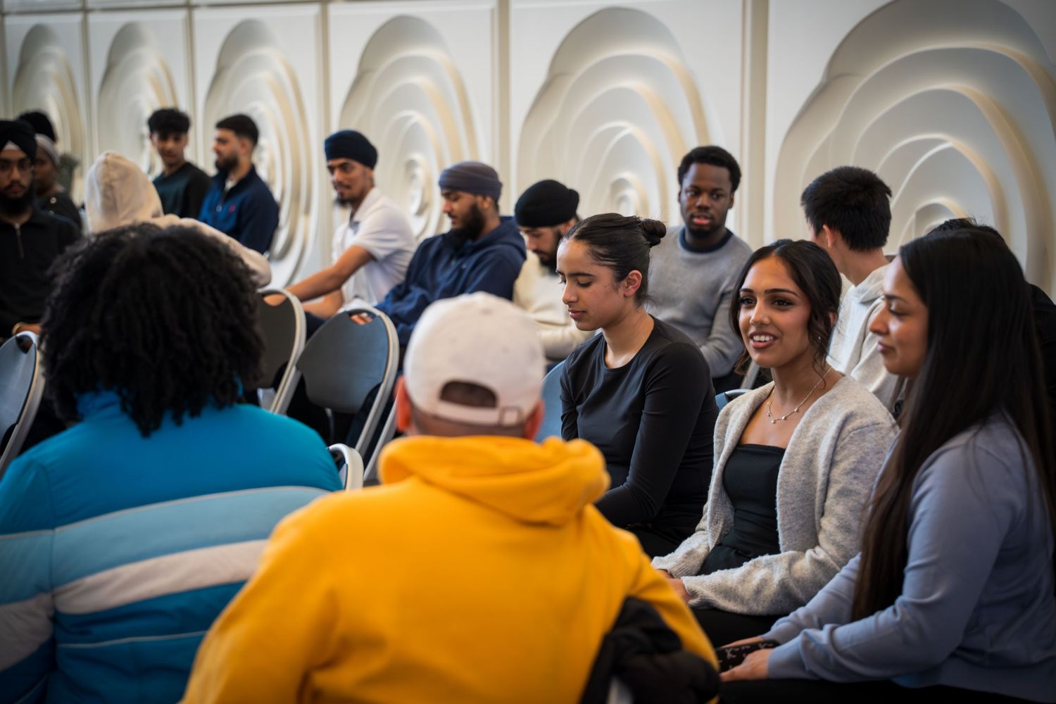 Audience members in casual attire listening attentively during an indoor presentation.