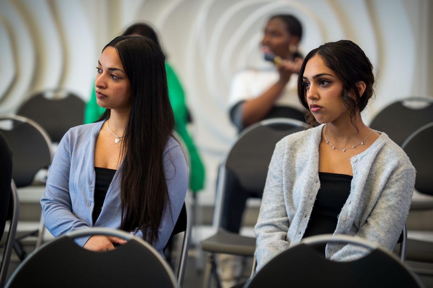 Panel participants in business attire discuss topics during a professional conference.
