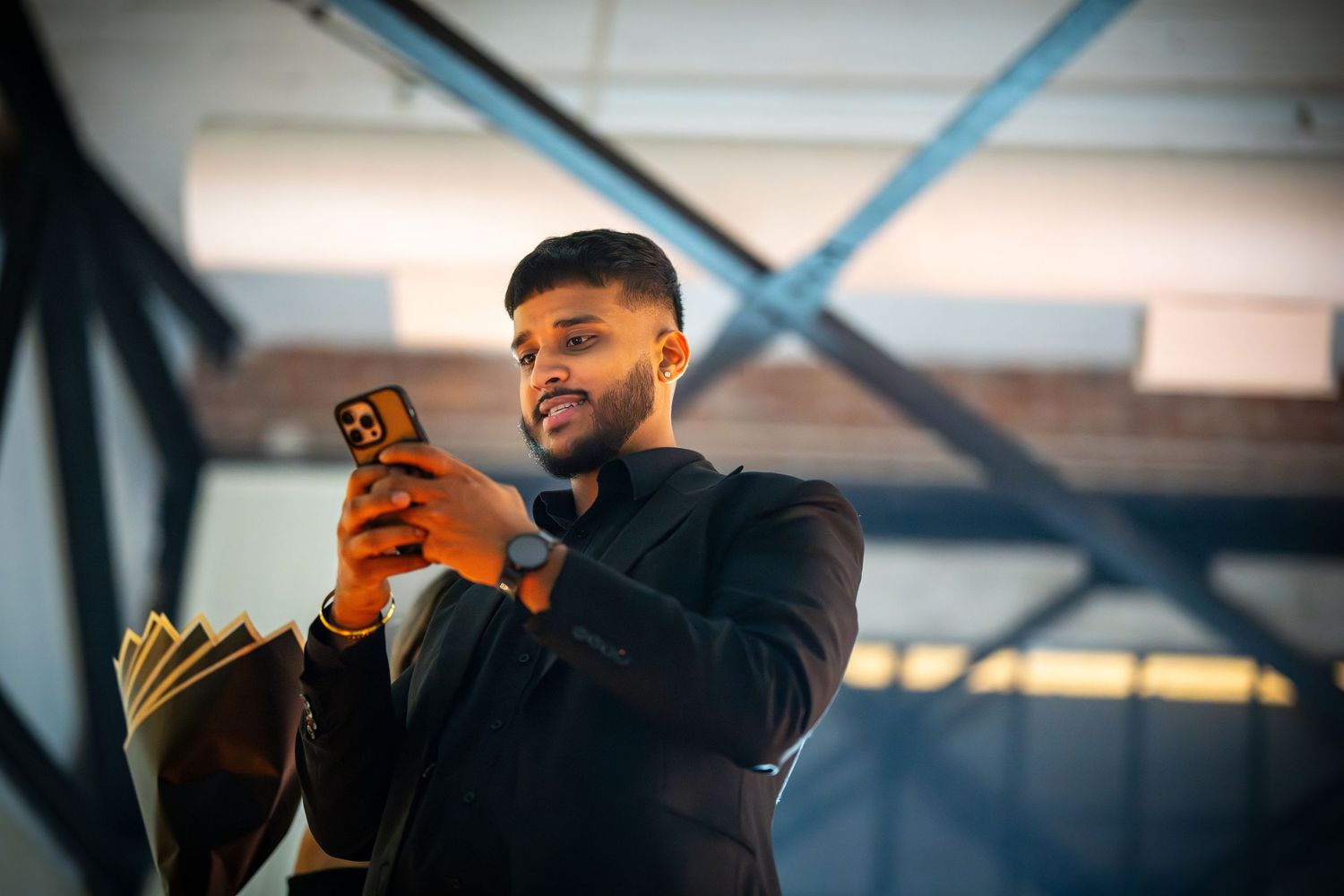 Person in black jacket looking at phone with blurred background.