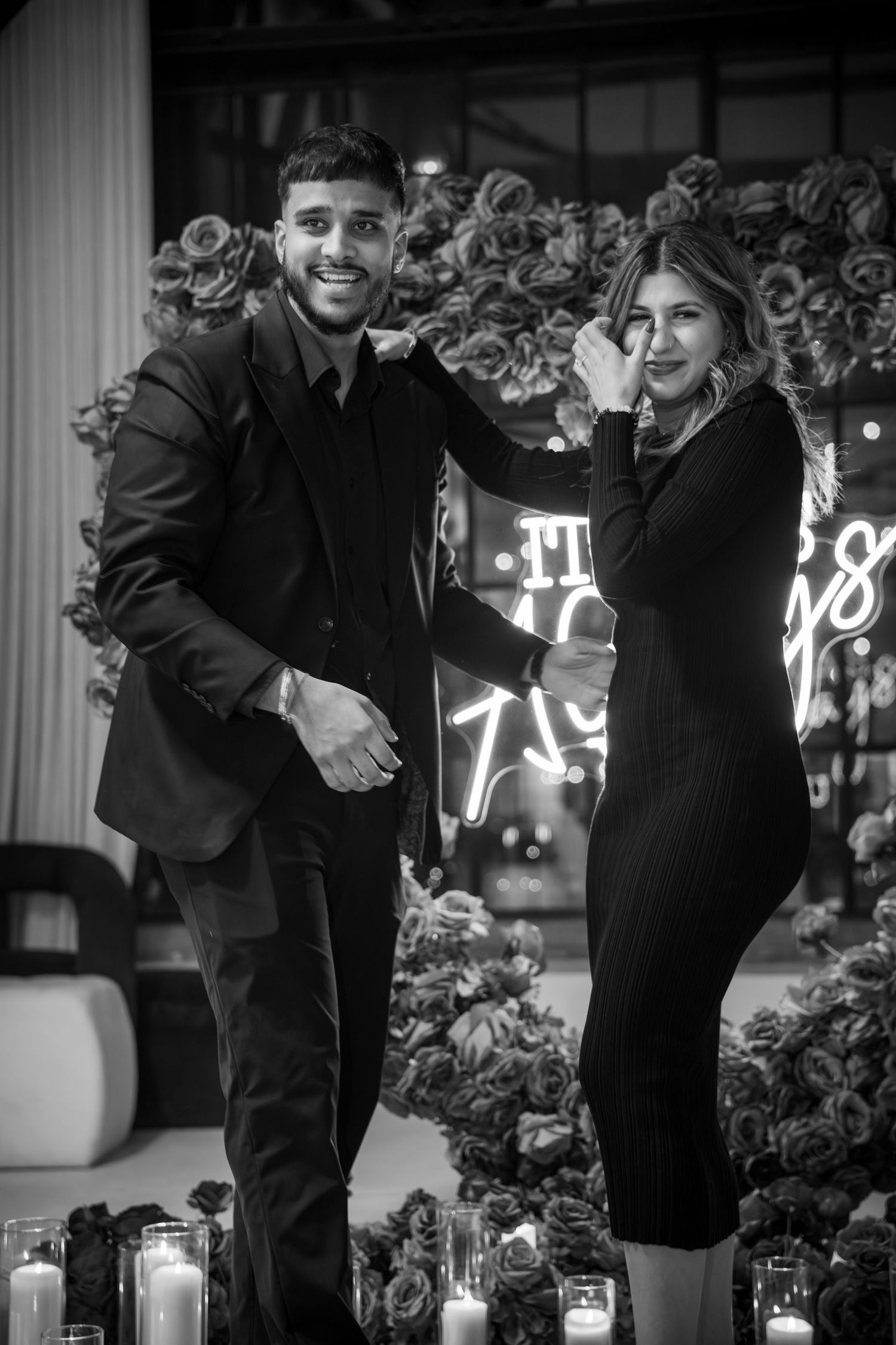Romantic engagement moment captured in black and white with floral decorations.