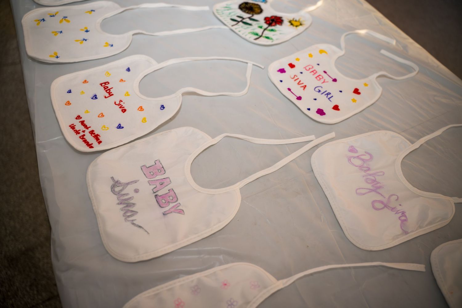 White baby bibs laid out with decorative designs and writing.