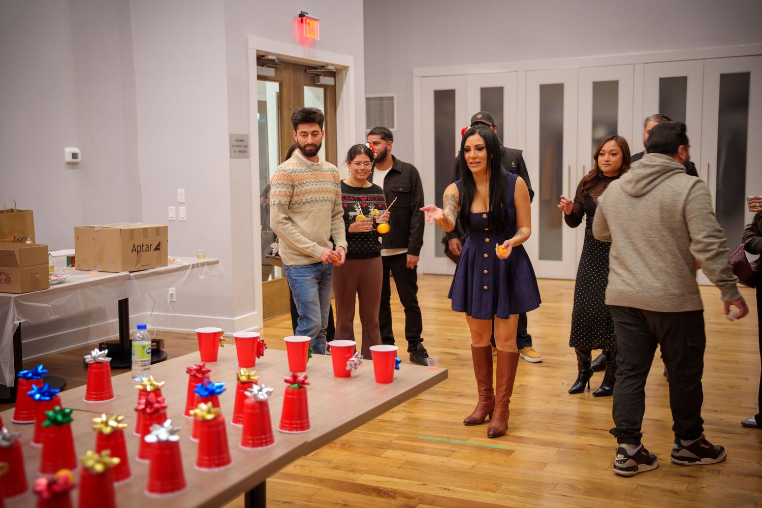 Row of red plastic cups arranged on hardwood floor at indoor party venue.