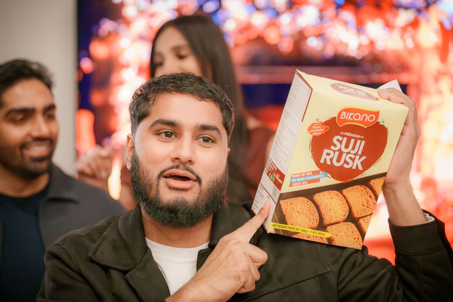 People enjoying snacks and beverages at a holiday celebration with colorful lights in background.