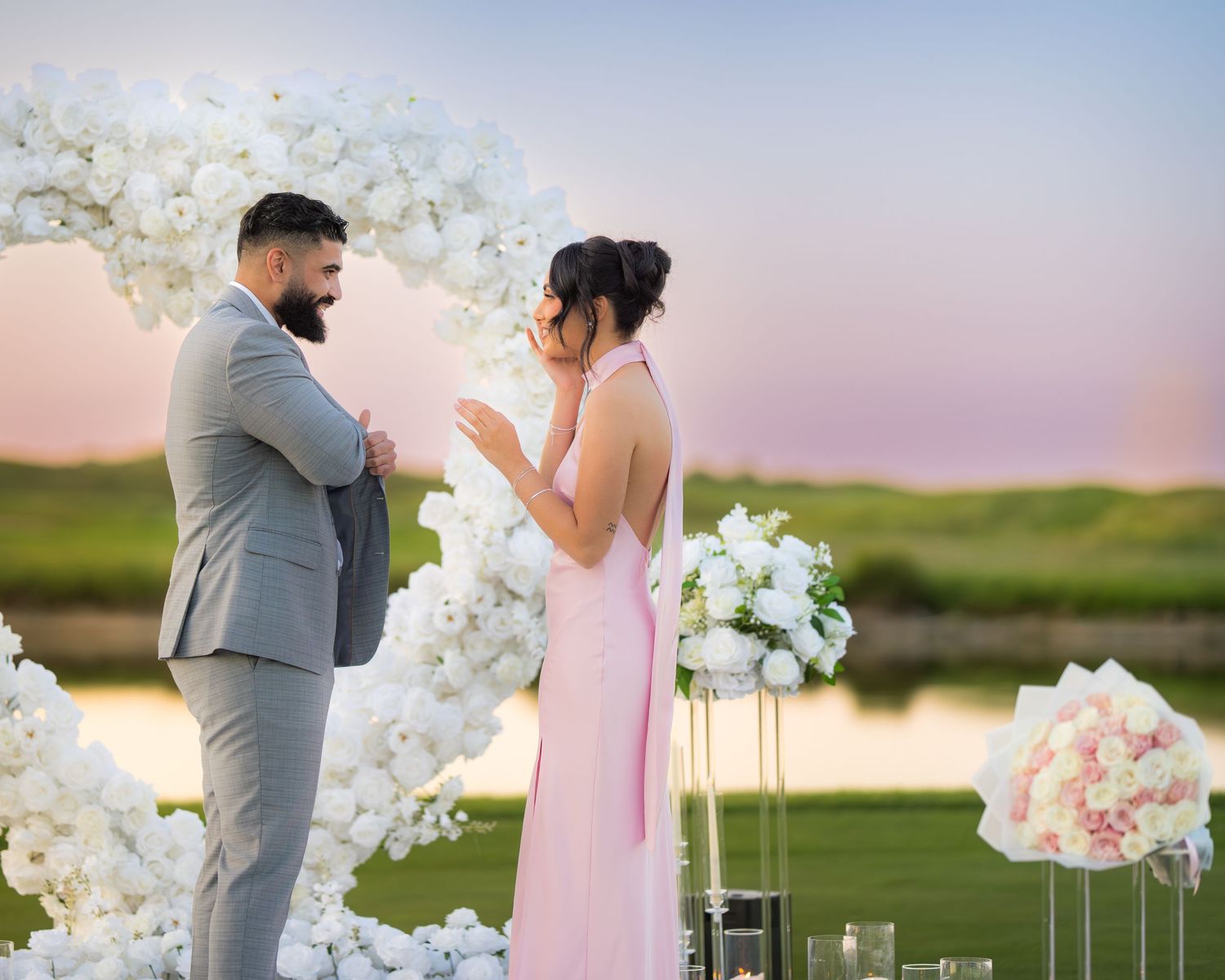 Sunset proposal scene with white orchid arch and illuminated candle pathway.