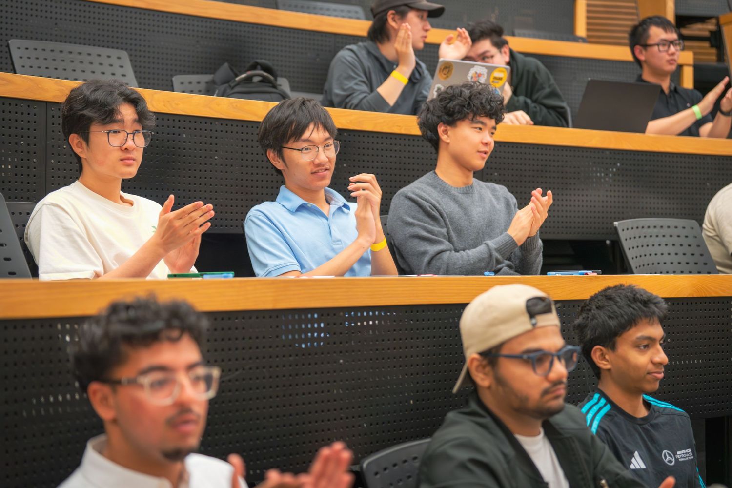 Students sitting in tiered lecture hall seating during a presentation.