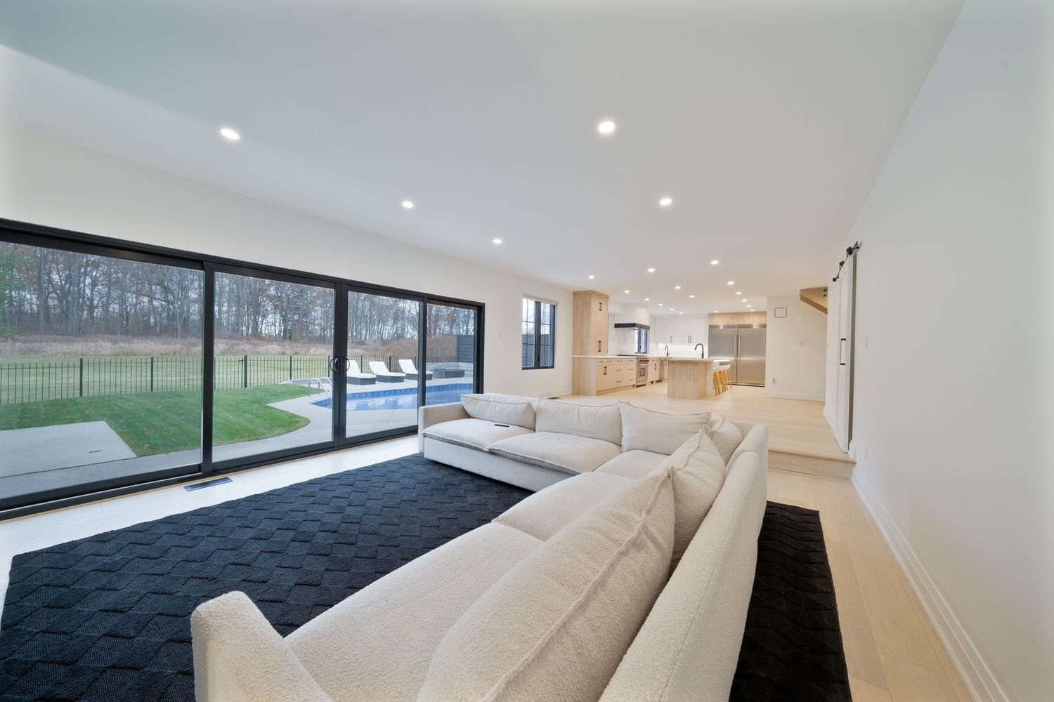 Modern white bedroom interior with large windows, black carpet, and recessed lighting showcases minimalist design.