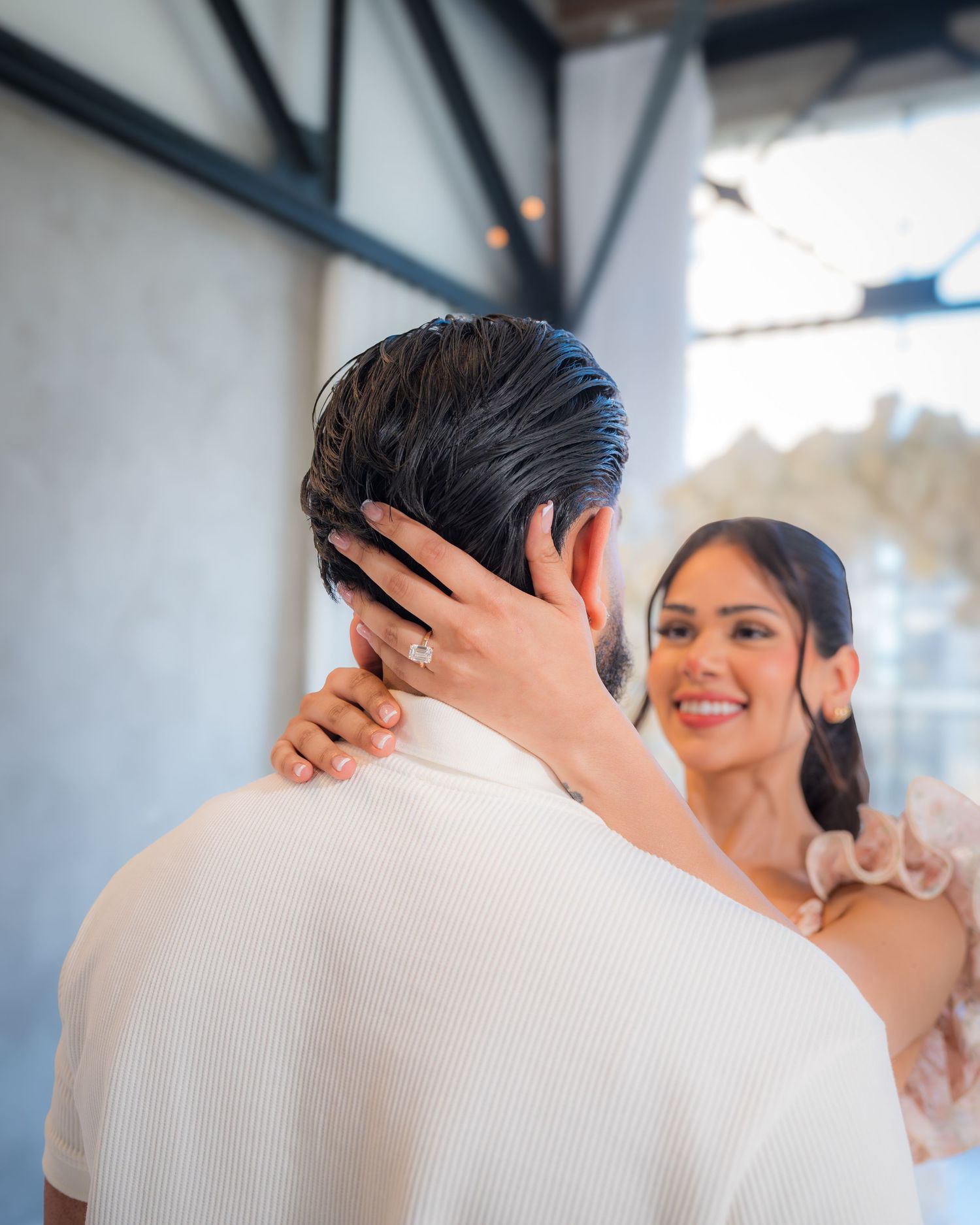 Woman smiling at man during romantic proposal moment, wearing floral dress with ruffled shoulders.
