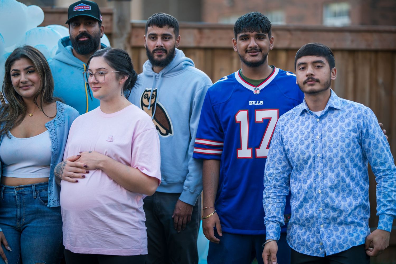 Group of six guests posing together at a backyard gender reveal party with balloon decorations.