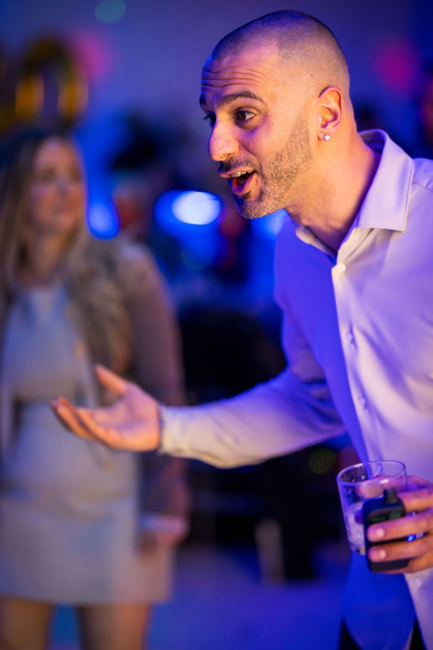 Person in white shirt dancing and gesturing energetically under blue party lights.