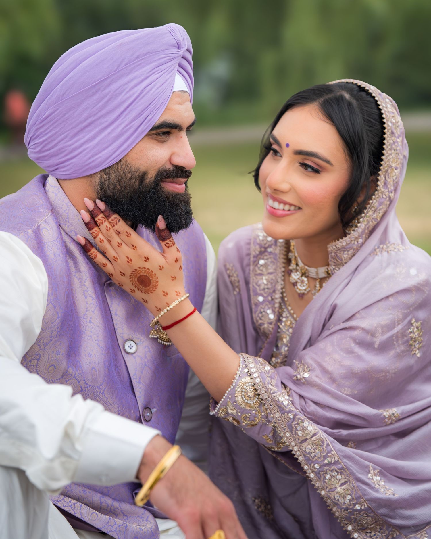 Romantic outdoor portrait session of couple in traditional South Asian wedding attire with purple accents.