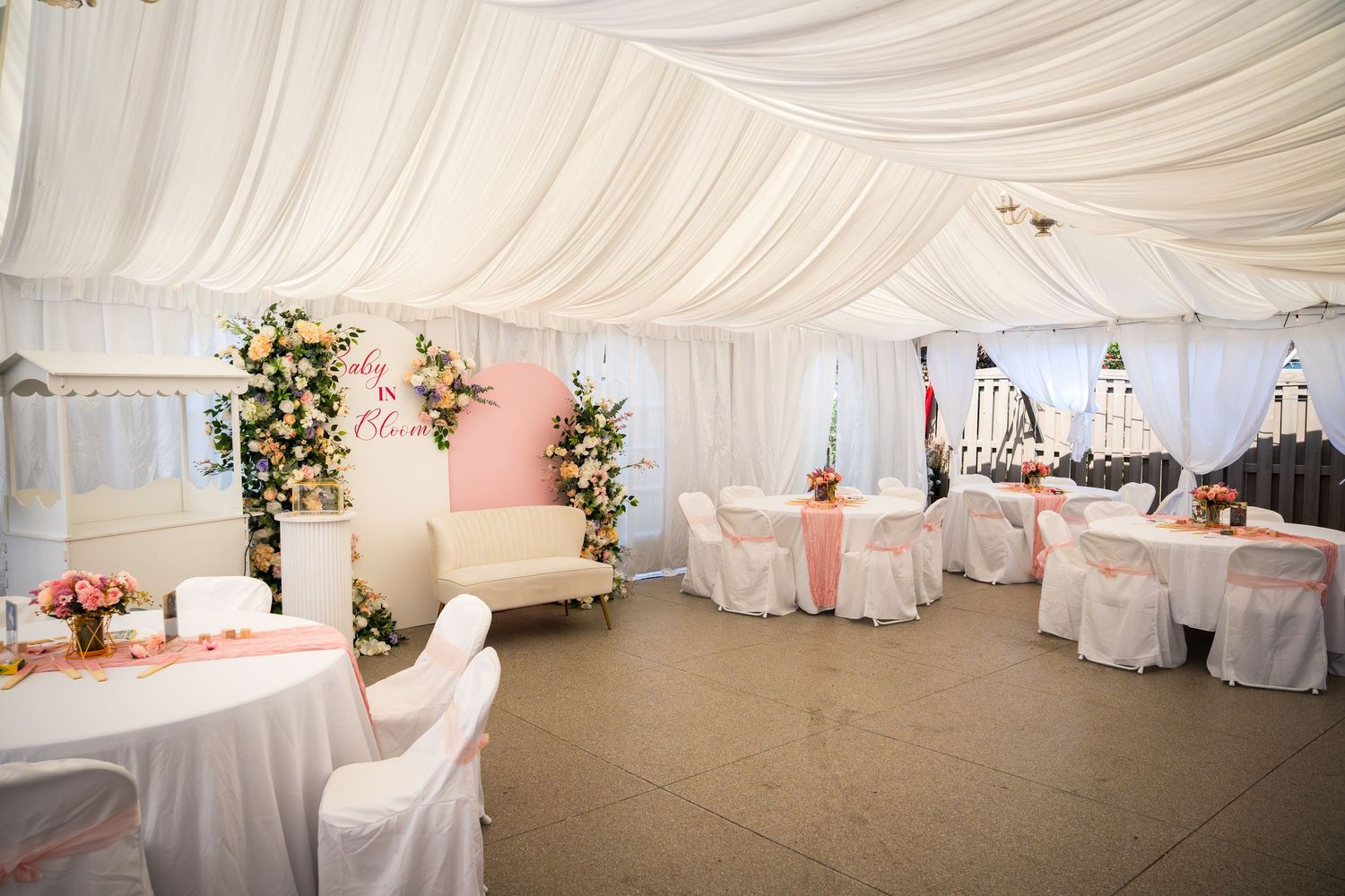 Panoramic view of an elegant white tent wedding reception space with pink accents.