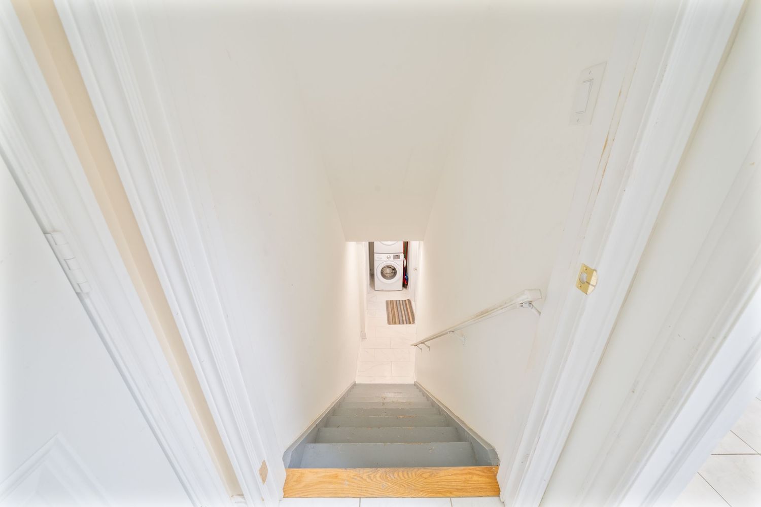 Minimalist white corridor with recessed lighting and wooden floor panels creating a clean aesthetic.