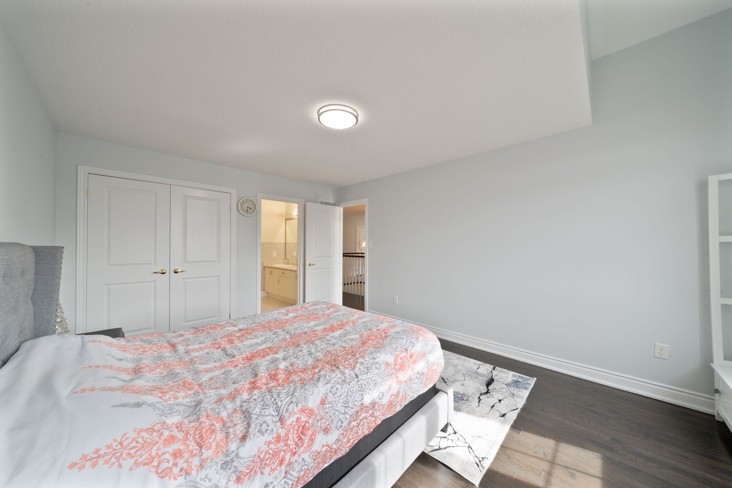 Modern bedroom with white walls, recessed lighting, and coral-patterned bedding on a queen bed.