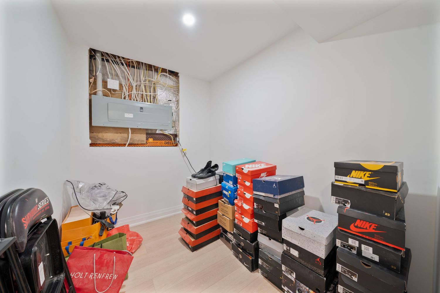 Storage room filled with stacked shoe boxes and athletic footwear against white walls with decorative artwork.