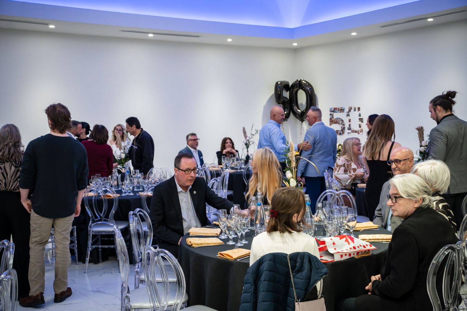 Event space with blue accent lighting and guests mingling at tables.
