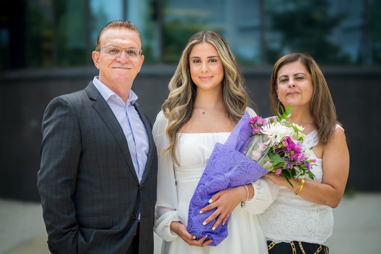 Group photo of three people standing together outdoors near a building.
