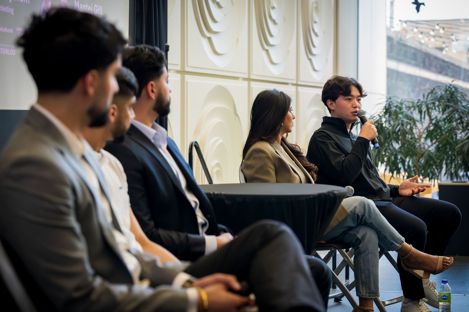 Audience members seated in rows listen attentively during an indoor conference presentation.