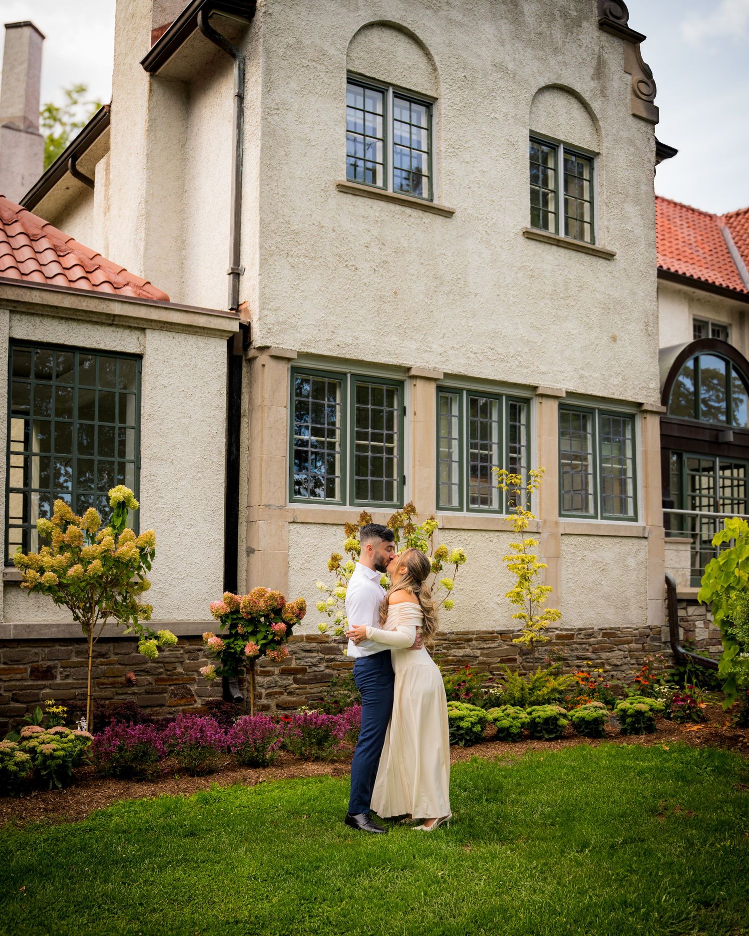 Wedding photo session outside historic stone building with garden landscape.