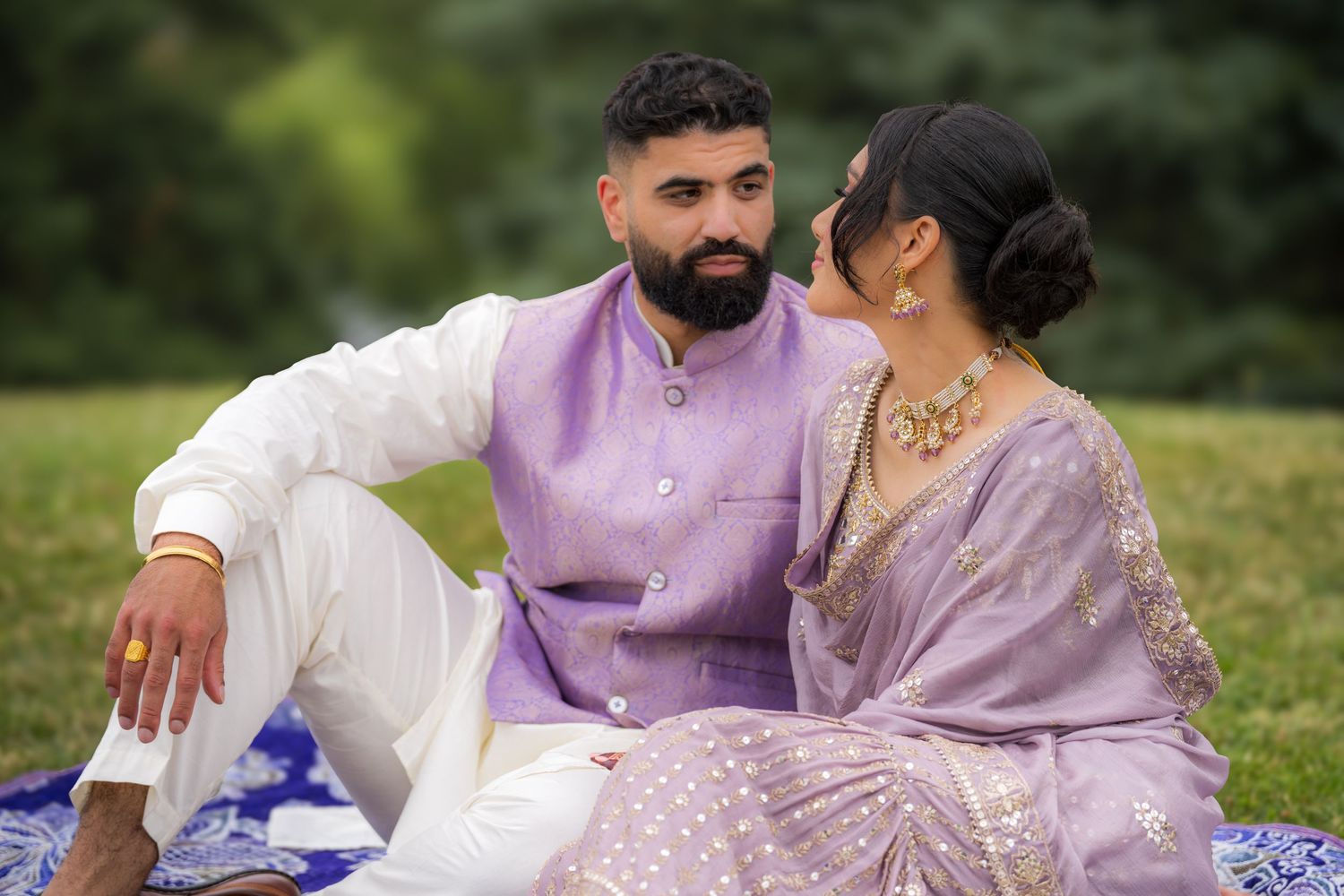 A couple in coordinated purple outfits share intimate moments during an outdoor photoshoot.